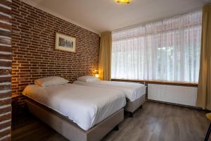 a bedroom with two beds and a brick wall at Buitengoed de Panoven in Zevenaar