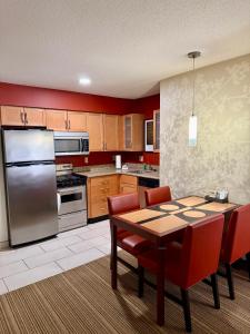 a kitchen with a table and chairs and a refrigerator at PrimeStay Extended Suites by IHG in Madison