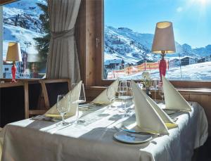 a table with a white table cloth and glasses and a window at Hotel Zürserhof in Zürs am Arlberg