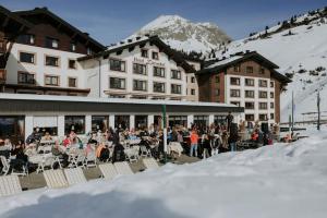 a group of people sitting outside of a building in the snow at Hotel Zürserhof in Zürs am Arlberg
