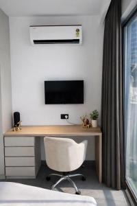 a desk with a television and a chair in a room at Yamunaviewnest in Noida