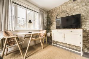 a living room with a desk and a tv on a brick wall at The Grain store in Cirencester