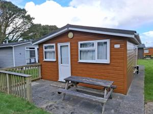 a tiny house with a picnic table in front of it at Cosy Corner Cabin in Saint Merryn