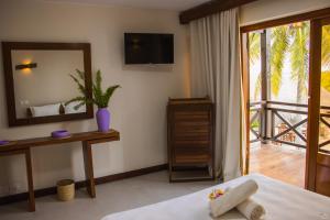 a bedroom with a bed and a mirror and a balcony at Hôtel Baobab Café in Morondava +54 photos