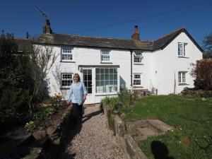 a woman standing in front of a white house at Trewetha Cottage Bed & Breakfast in Port Isaac