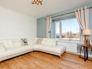 a living room with a white couch and a window at Knocknahighle in Cromdale