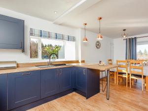 a kitchen with blue cabinets and a dining room at Knocknahighle in Cromdale