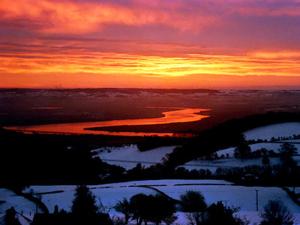 a sunset over a body of water in the snow at Vale View Cottage in Cinderford +3 photos