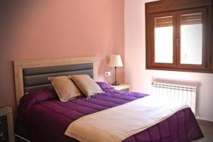 a bedroom with a purple bed with a window at Apartamentos Aldeas de Pontones in Pontones