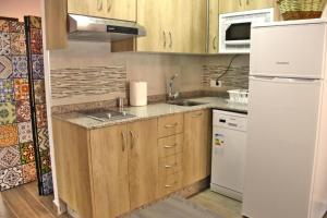 a kitchen with wooden cabinets and a white refrigerator at Apartamentos Aldeas de Pontones in Pontones