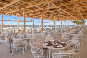 a restaurant with white tables and chairs and the ocean at Pickalbatros Dana Beach Resort - Aqua Park in Hurghada +271 photos