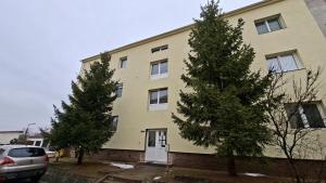 a building with two trees in front of it at Tiszti Szálló Apartman in Verpelét