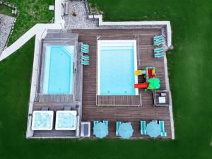 an overhead view of two swimming pools and lawn chairs at Hotel Grohmann in Campitello di Fassa +53 photos