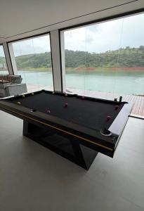 a black pool table in a room with windows at Resilience Igaratá in Igaratá