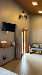 a bedroom with a bed and a flat screen tv at Vila Florença Chales in Santa Teresa