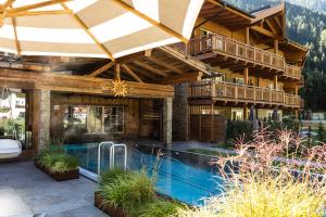 a house with a swimming pool and an umbrella at Living & Spa Vitalhotel Edelweiss in Neustift im Stubaital