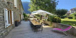 a wooden deck with a table and chairs and an umbrella at Les Échappées Belles - Gîtes et chambres d'hôtes 4 étoiles in Antignac