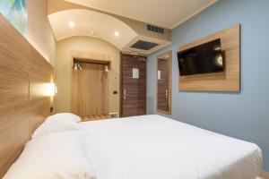 a bedroom with a white bed and a flat screen tv at Wyndham Garden Conegliano in Conegliano