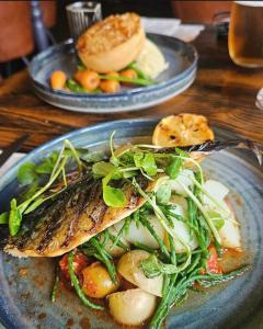 a plate of food with fish and vegetables on a table at The Huntsman in Norwich +8 photos