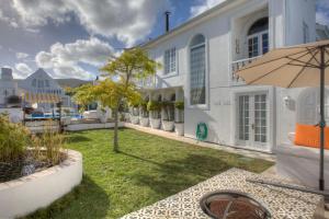 a courtyard of a white building with an umbrella at Our Hermanus House in Hermanus