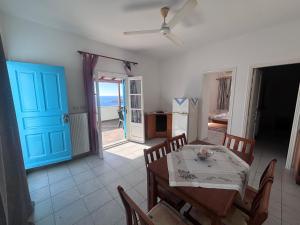 a dining room with a table and a blue door at Sunset Studio Apartments in Kalymnos
