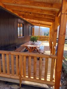 a wooden porch with a wooden table on a deck at Cabaña Lefuco, Curacautin in Manzanar