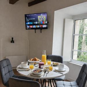 a dining room table with food and a tv on the wall at L'Âtre Angevin - cheminée d'époque - Doutre in Angers