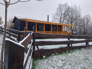 a house in the snow with a wooden fence at Cabaña Lefuco, Curacautin in Manzanar