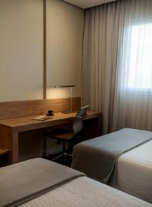 a hotel room with a desk and two beds at Rio Hotel by Bourbon Campinas in Campinas