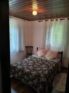a bedroom with a bed and two windows at Refúgio da Serra - com lareira - 900m do Capivari in Campos do Jordão