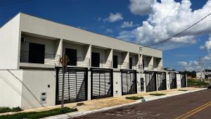 a white building with black gates and a street at Flat2 Aconchegante com Cozinha Completa in Sinop