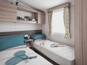 a small room with two beds and a window at Riverside Essential Clover Caravan Pet 1 in Wooler +2 photos