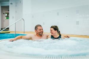 a man and a woman in a hot tub at Riverside Essential Clover Caravan Pet 1 in Wooler
