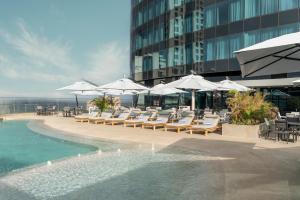 a pool with chairs and umbrellas next to a building at Radisson Blu Hotel, Durban Umhlanga in Durban