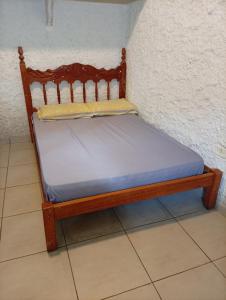 a bed with a wooden frame in a room at Sol & mar Hospedagem - Boqueirão Sul Via Balsa Cananéia in Ilha Comprida