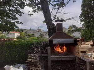 an outdoor grill with a fire in a yard at Gîte des Grands Causses in Millau