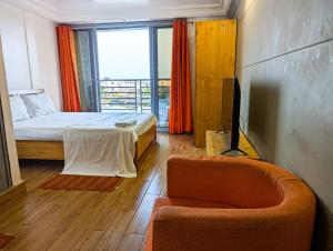 a bedroom with a bed and a chair and a tv at Résidence Houé in Cotonou