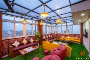 a large room with couches and tables and windows at Zostel Varanasi in Varanasi