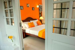 um quarto com uma cama com uma parede laranja em The Francis Residence em Cochin