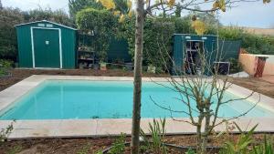 a swimming pool in a garden with a green shed at piedameretnature in Lagord