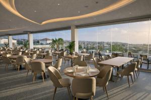 a restaurant with tables and chairs and large windows at Hotel Baia Grande in Albufeira