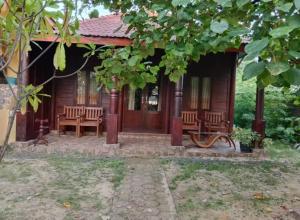 a house with two benches in front of it at Omah Laut Bondo Jepara - by the beach, direct view of the sea, great base for water sports in Margokerto