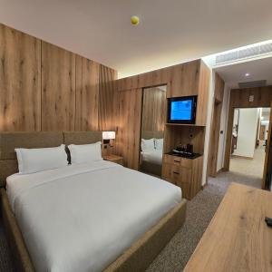 a bedroom with a large bed and a flat screen tv at BAZ Hotel Airport Road in Baghdād +43 photos