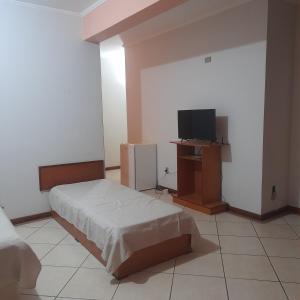 a bedroom with a bed and a flat screen tv at Village Hotel in São Borja