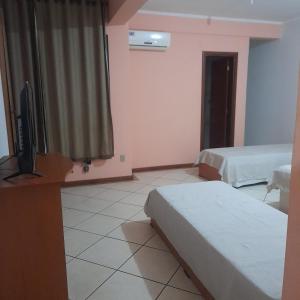 a hotel room with two beds and a television at Village Hotel in São Borja