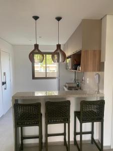a kitchen with two chairs and a counter with two lights at Beach Class Verano 01 A in Ipojuca