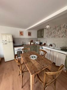 a kitchen with a wooden table with chairs and a refrigerator at La Romance in Acy-Romance
