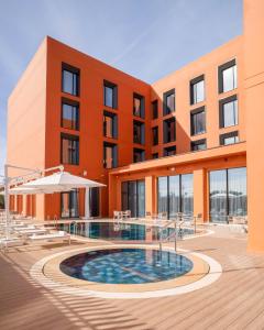a hotel with a swimming pool in front of a building at Hampton By Hilton Ben Guerir in Benguerir