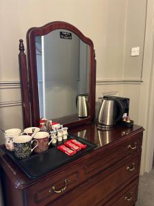a mirror on top of a wooden dresser with cups and coffeeisers at Belvedere Lodge in Cork