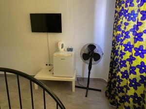 a room with a fan and a table with a television at une chambre dépaysante in Tarrafal